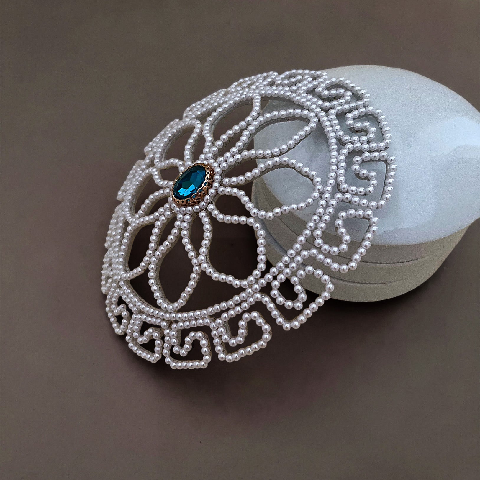 Side profile view of a domed pearl bridal hair cage, demonstrating the 3D curved structure designed to perfectly fit over a classic bridal bun.
