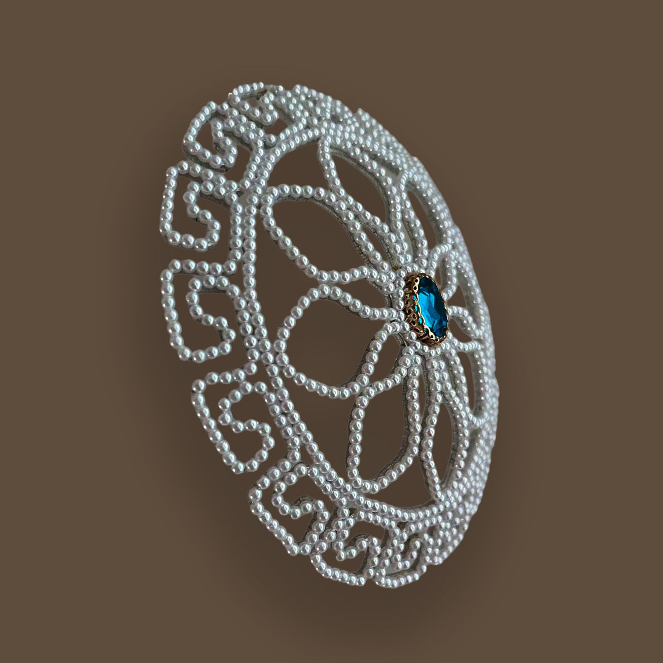 Side-angle profile of a structured vintage style pearl chignon cage, showing the 3D domed shape designed to perfectly fit a wedding updo, resting on a warm brown background.