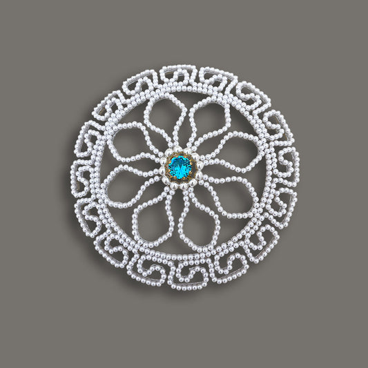 Overhead view of a round vintage pearl bridal bun cover featuring an intricate floral bead pattern and a bright blue central gemstone.