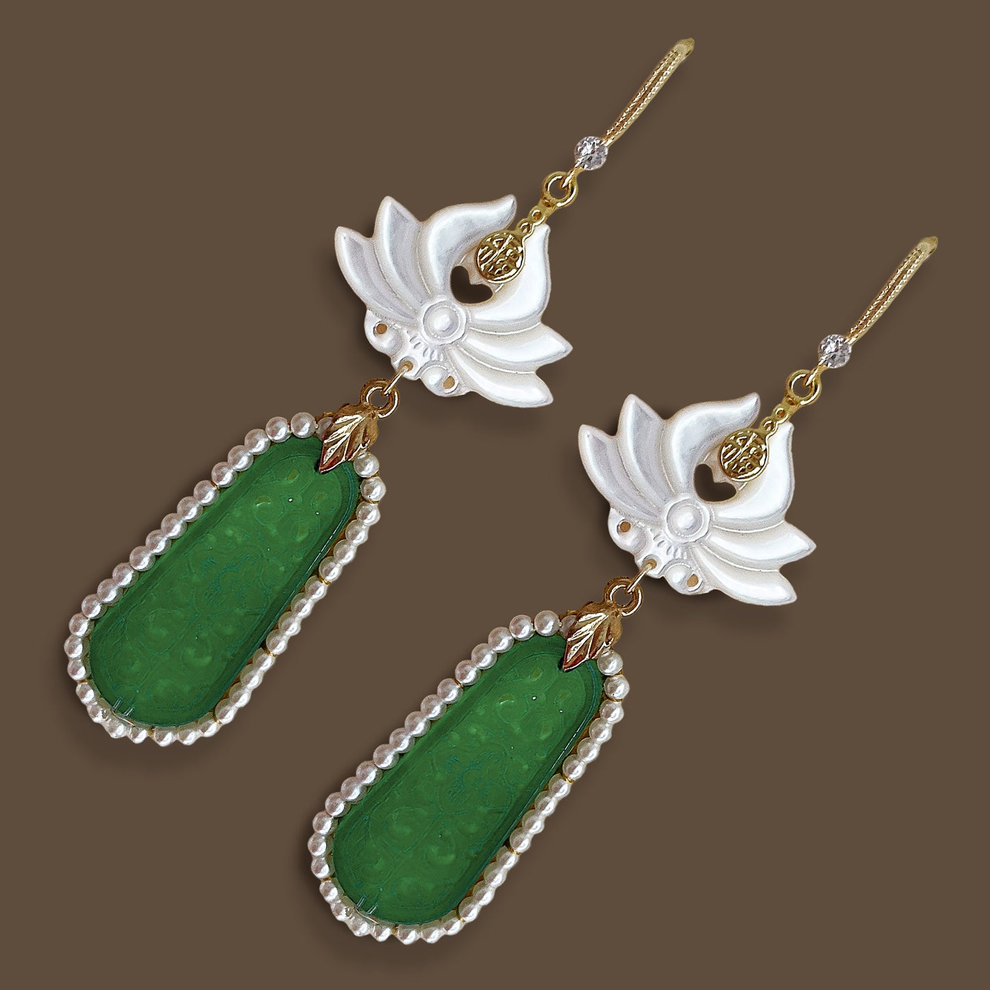 Close up overhead view of handcrafted botanical lotus and jade colored stone drop earrings with gold details
