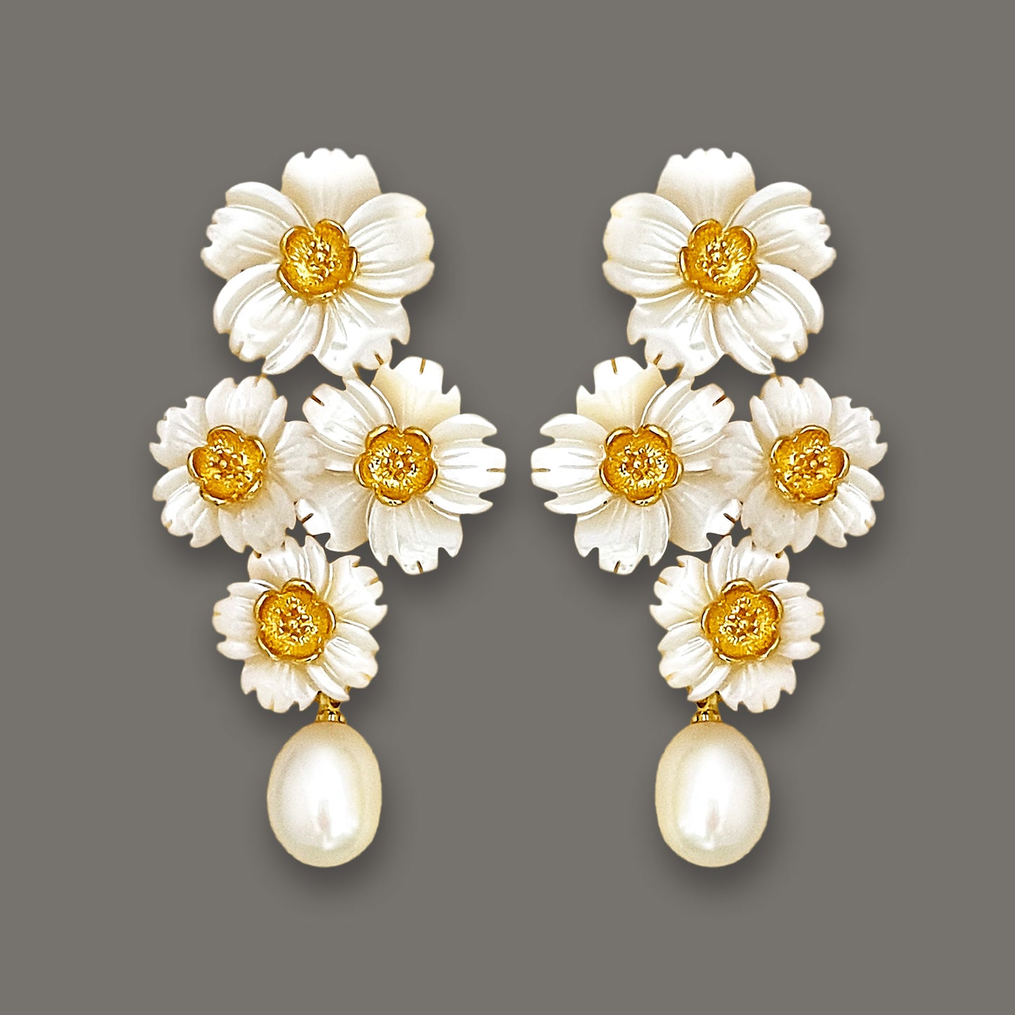 Statement mother-of-pearl daisy cluster earrings with dangling pearls on dark background