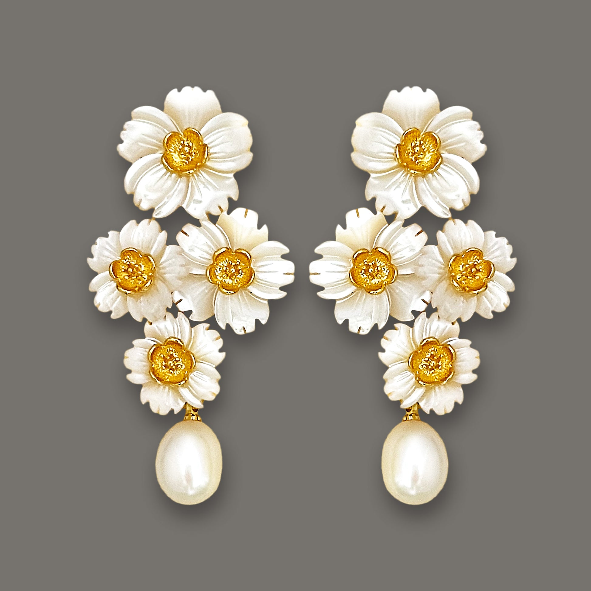 Statement mother-of-pearl daisy cluster earrings with dangling pearls on dark background