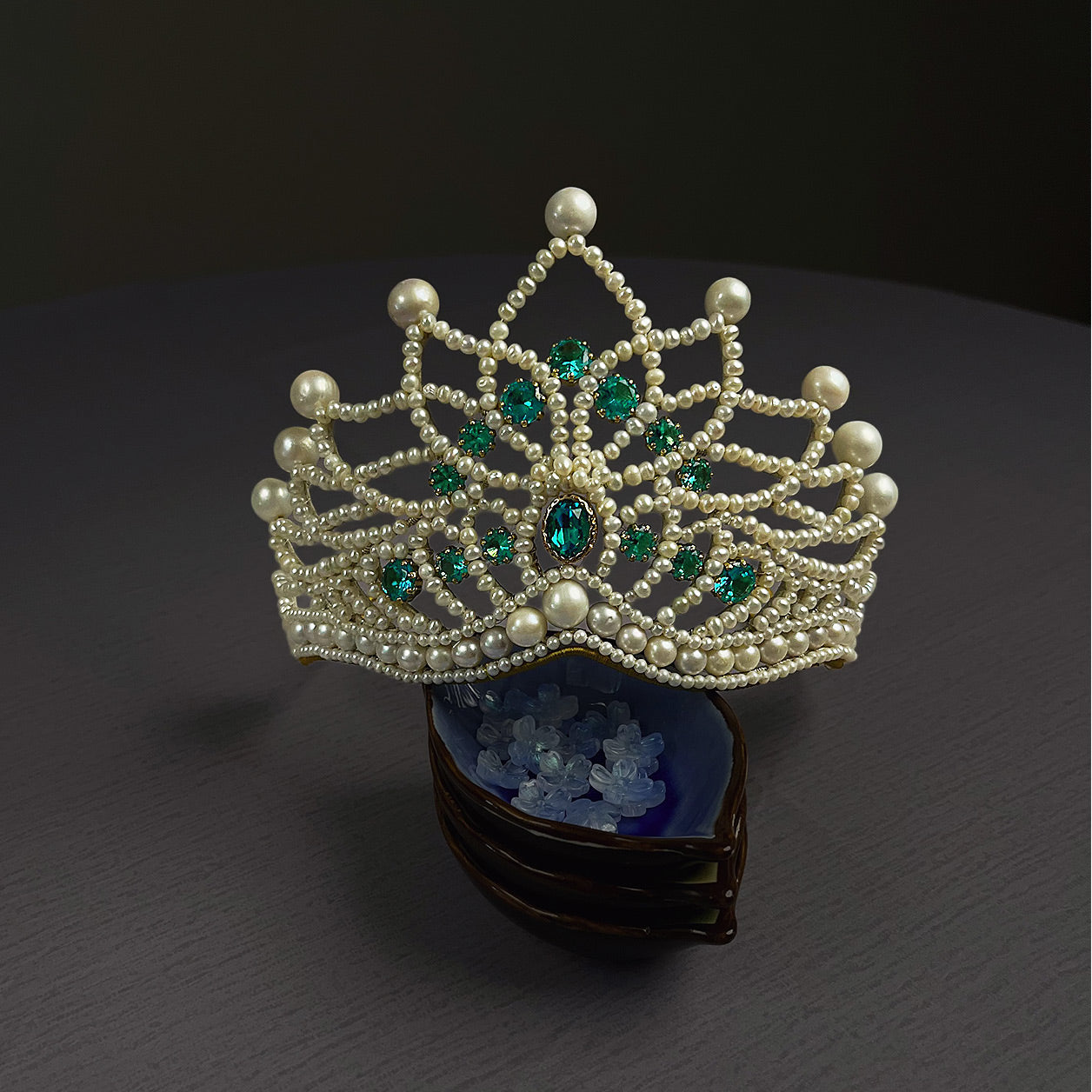 Front view of a handmade vintage style bridal crown featuring woven freshwater pearls and brilliant blue zircon stones.