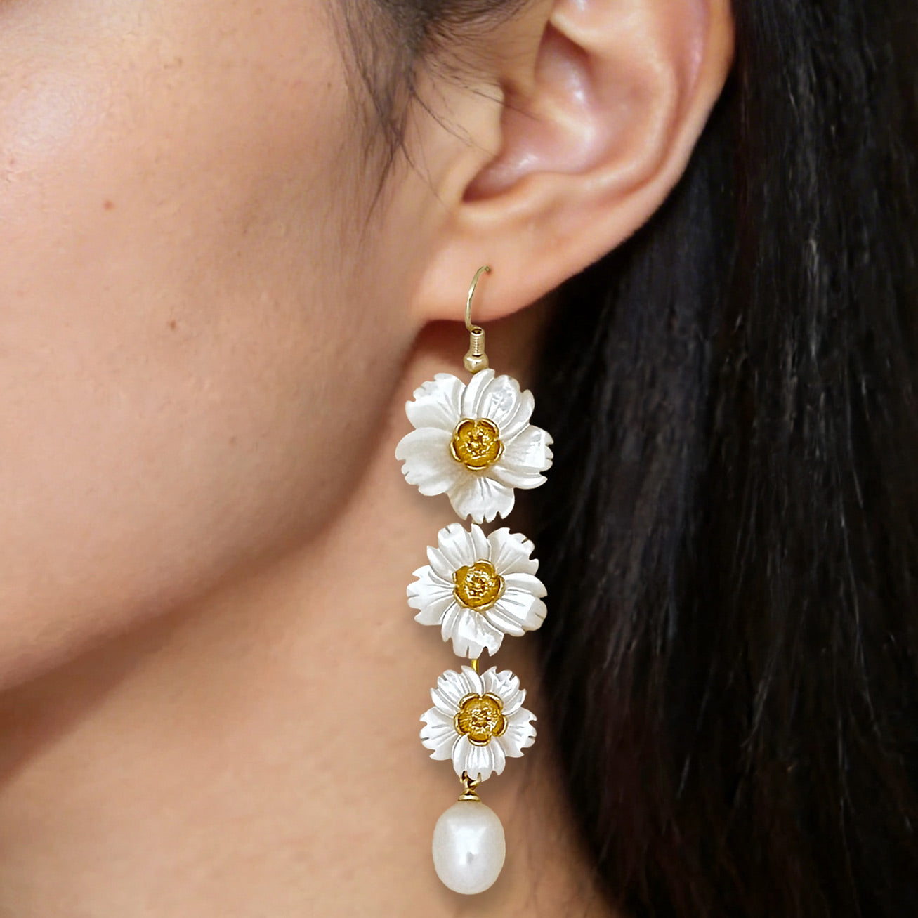 Close up of elegant long floral pearl earrings worn on the ear