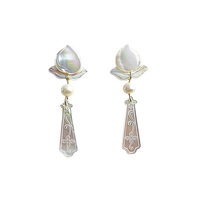 Product shot of the carved mother of pearl and freshwater pearl wedding earrings isolated on a clean white background.