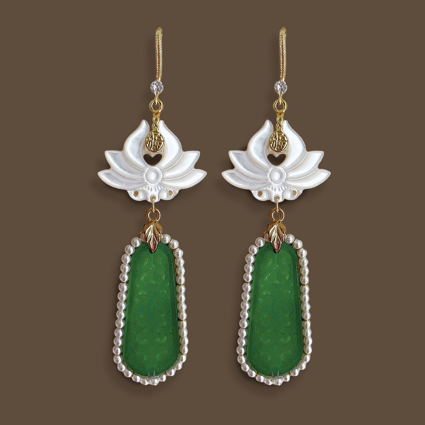 ymmetrical flat lay of vintage style mother-of-pearl flower earrings with long green geometric pendants
