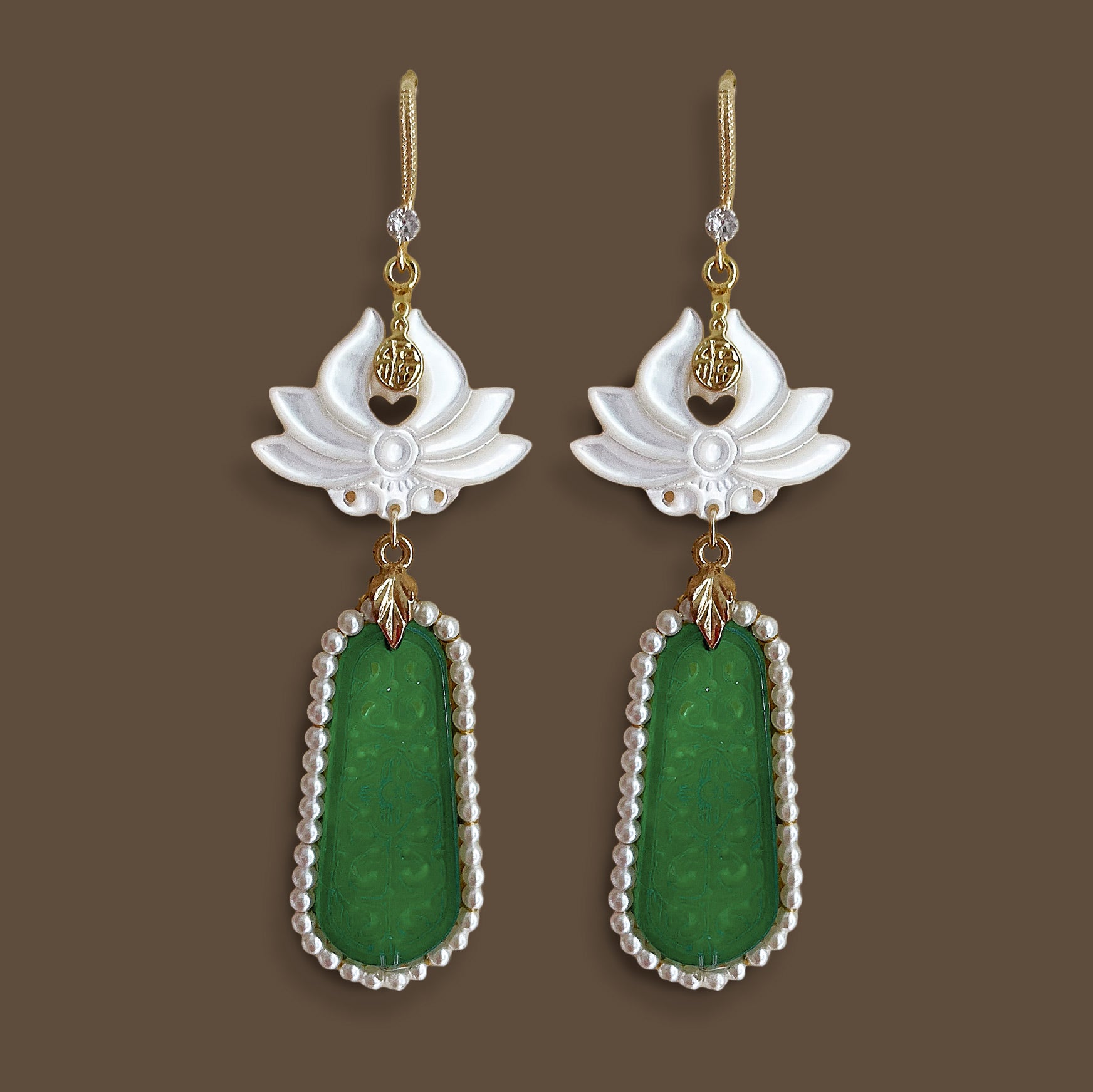 ymmetrical flat lay of vintage style mother-of-pearl flower earrings with long green geometric pendants