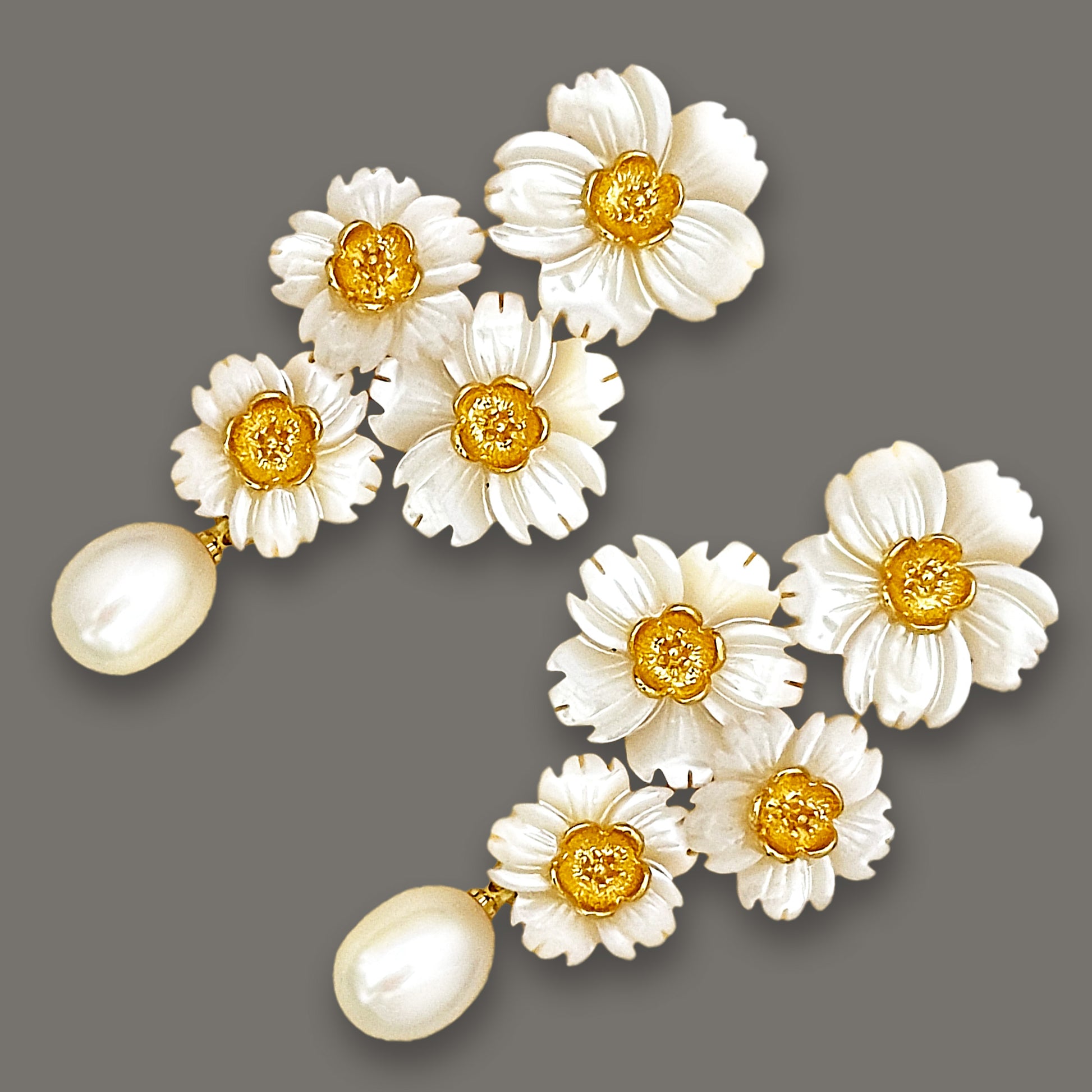 Overhead view of intricate multi-flower botanical earrings featuring carved petals and pearl accents