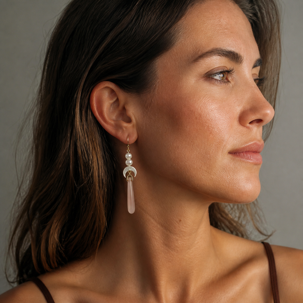 Side view of a beautiful elegant model wearing Celeste long pink agate and pearl dangle earrings, showcasing romantic bridal style.