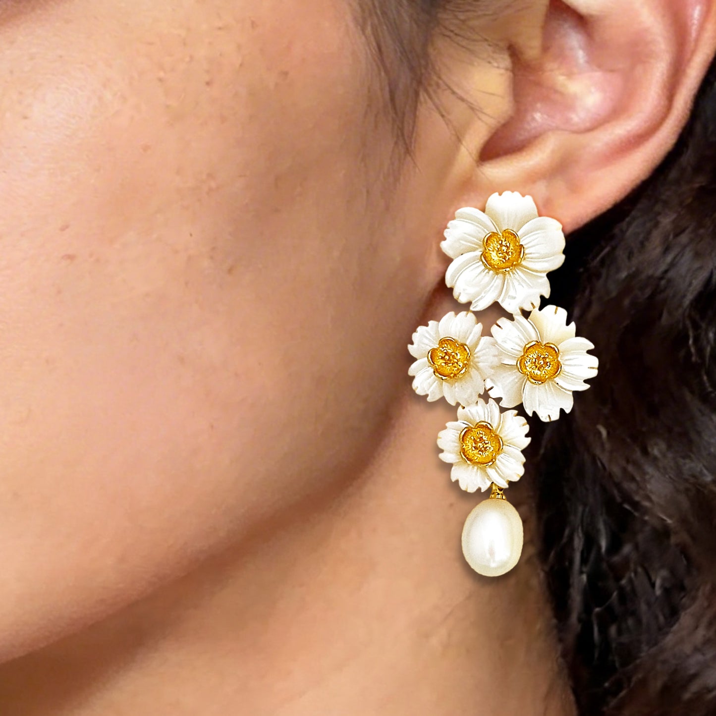 Detailed close up of a delicate multi-daisy bouquet ear drop worn on the earlobe