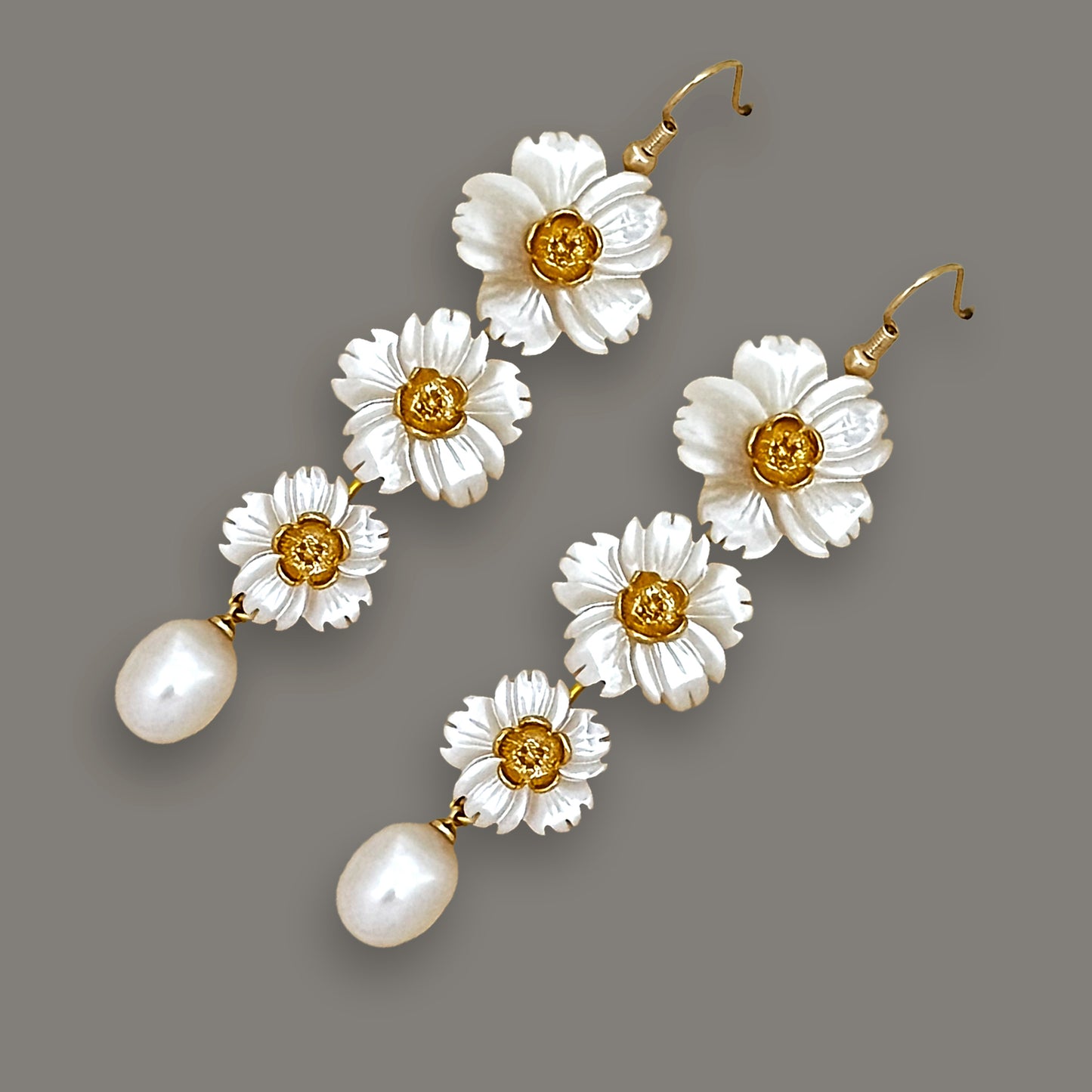 Angled view of three-flower stacked shell earrings with teardrop pearls