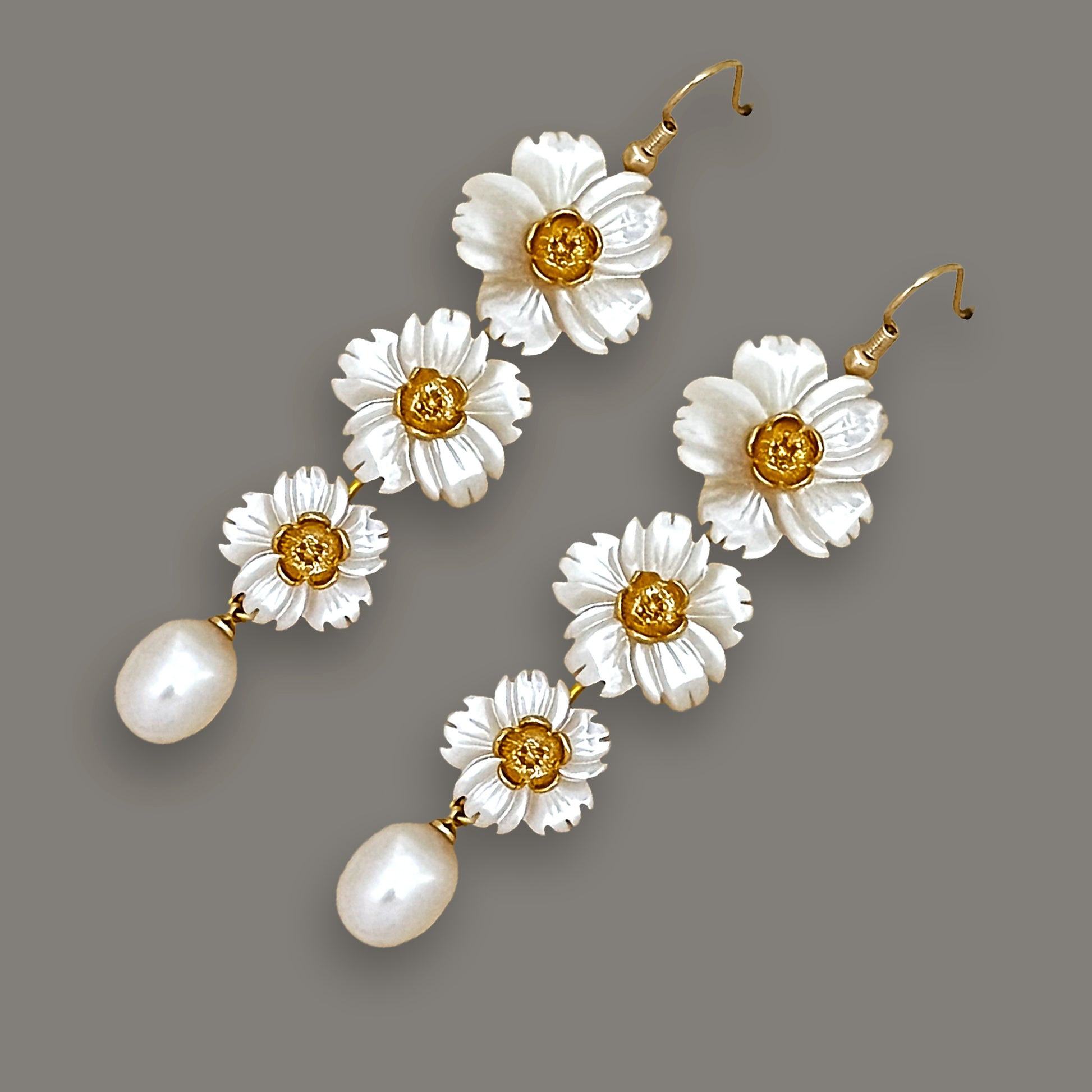Angled view of three-flower stacked shell earrings with teardrop pearls