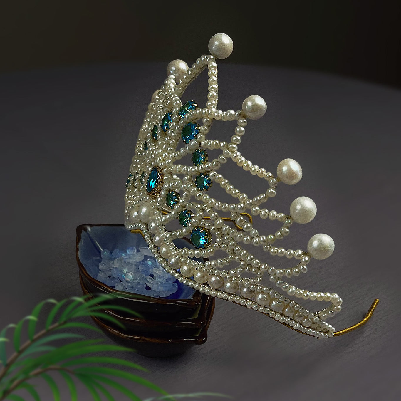 Angled side view of the wire-wrapped pearl wedding tiara showing the intricate copper wire structure and blue zircon accents.
