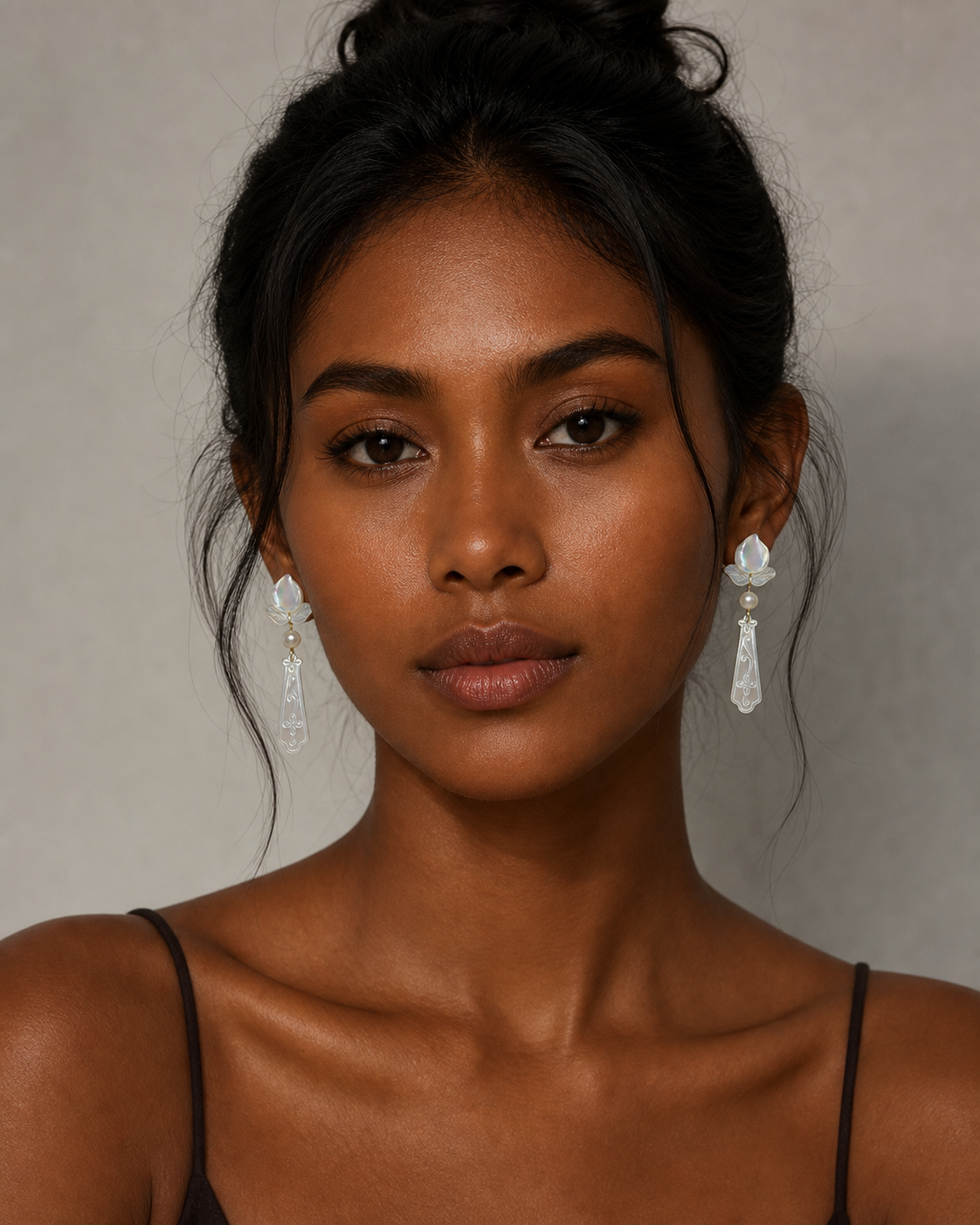 A bridal model wearing the carved mother of pearl statement earrings, highlighting the luminous shimmer under warm lighting.
